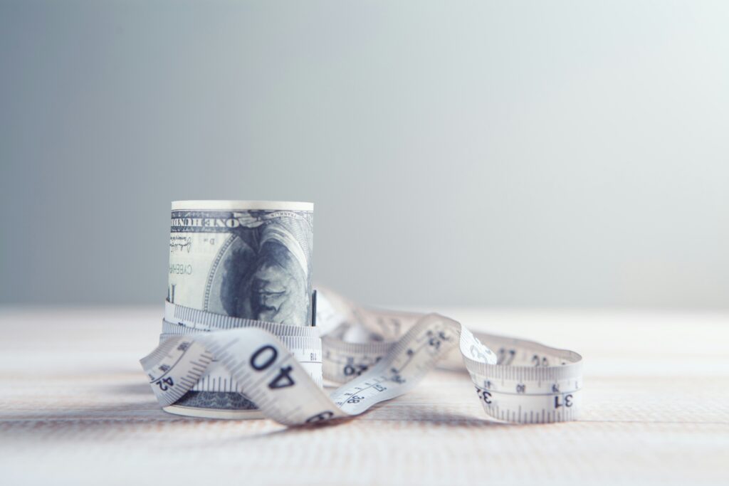 Measuring tape wrapped around rolled banknotes, representing the relationship between certified legal translation rates and professional value.